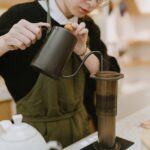 A cup of freshly brewed coffee next to a kettle, showing how to avoid bitter coffee