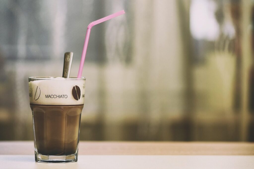 A glass French press filled with warm milk and thick foam