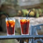 A tall glass of iced coffee made from cold brew concentrate, with a jar behind it