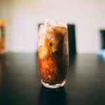 An iced latte in a tall glass with espresso swirling into cold milk over ice