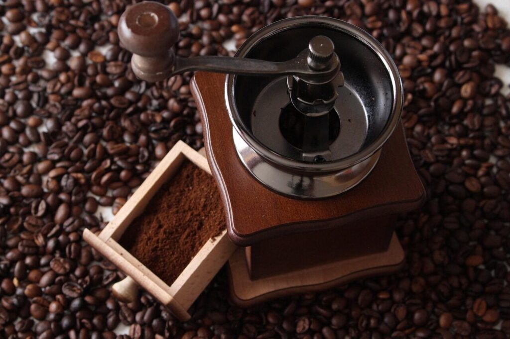 Coarsely ground coffee beside a hand grinder on a kitchen counter