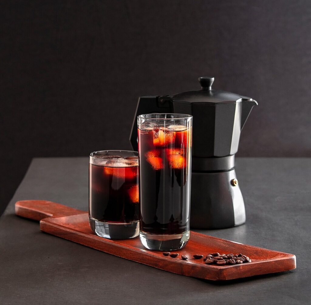 Dark coffee ice cubes in a tray beside a glass of milk