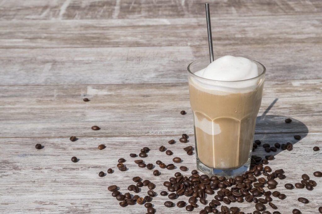 Diluted cold brew poured over ice in a glass with a splash of milk