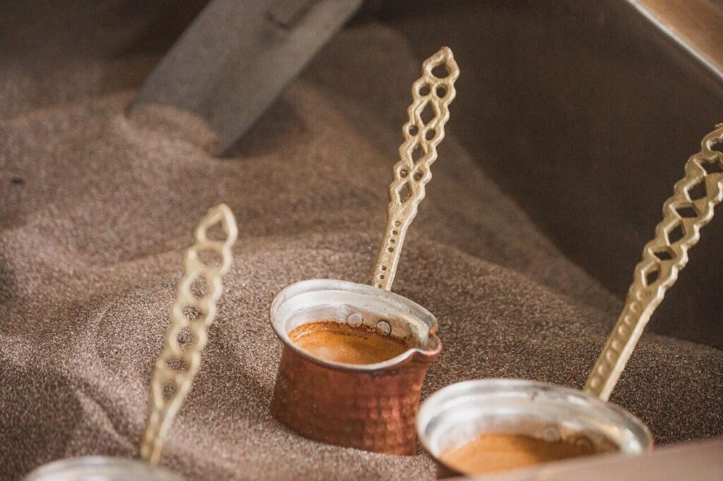 Finely ground Turkish coffee in a small copper pot beside a cup