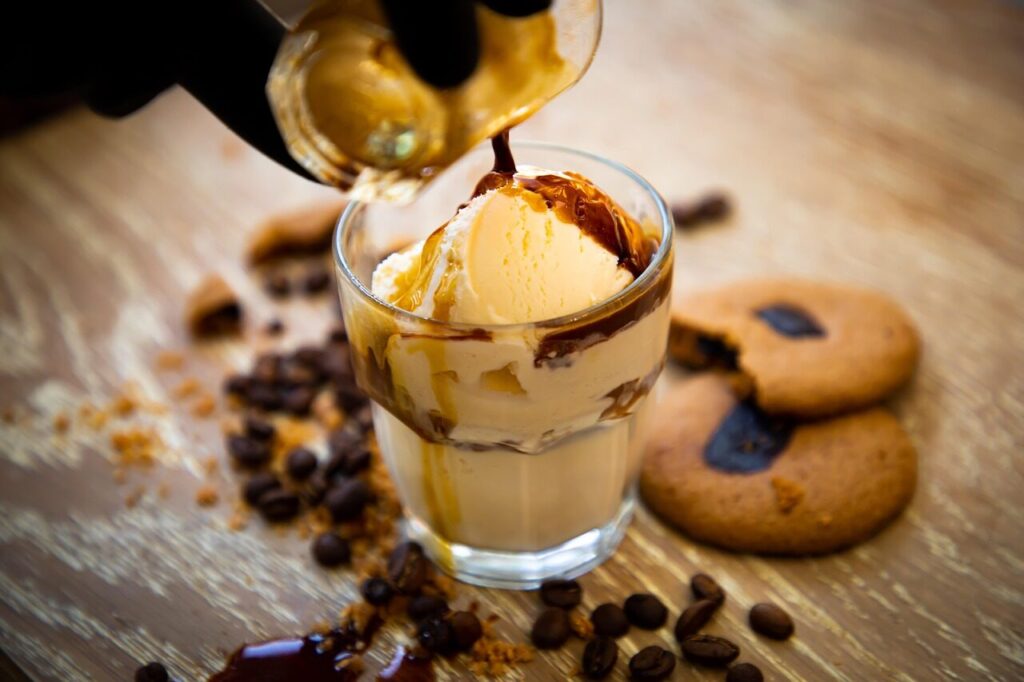 Fresh espresso pouring over milk and ice cubes in a clear glass