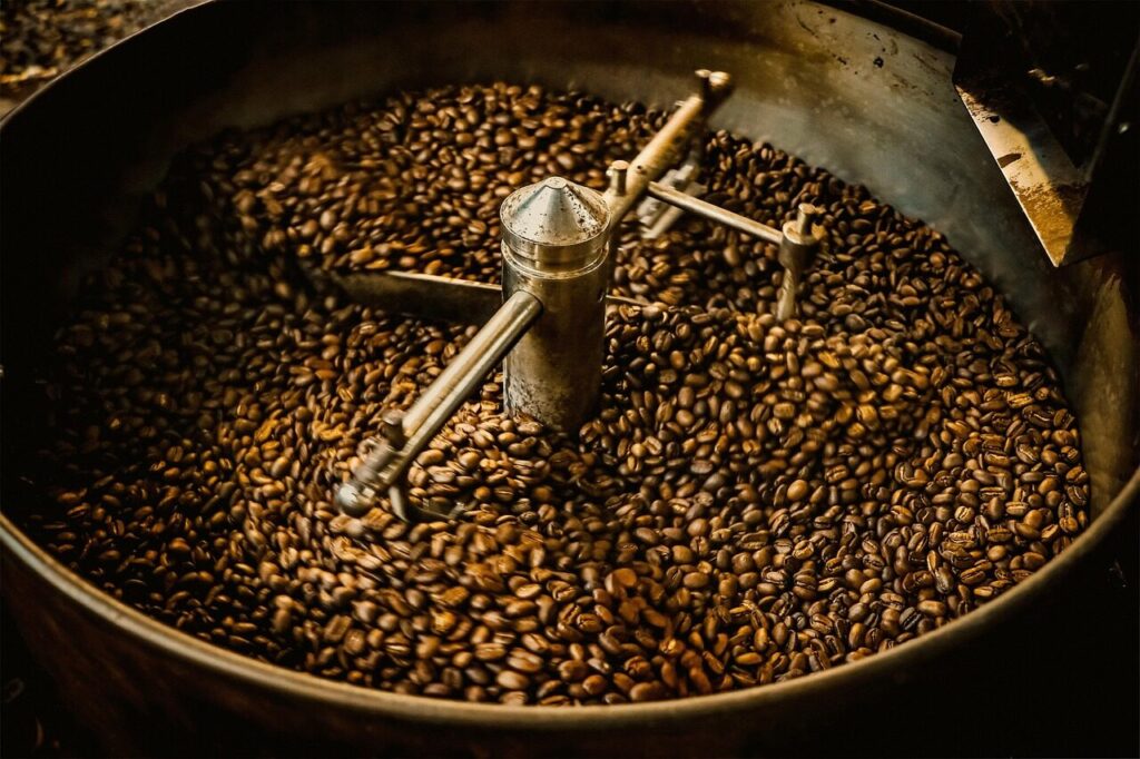 Freshly roasted coffee beans spilling from a roasting machine into a cooling tray