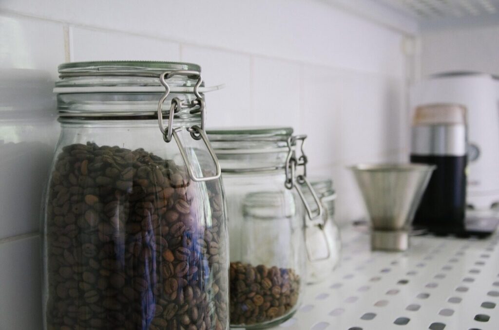 Glass jar of coffee beans sitting on an open kitchen shelf in daylight