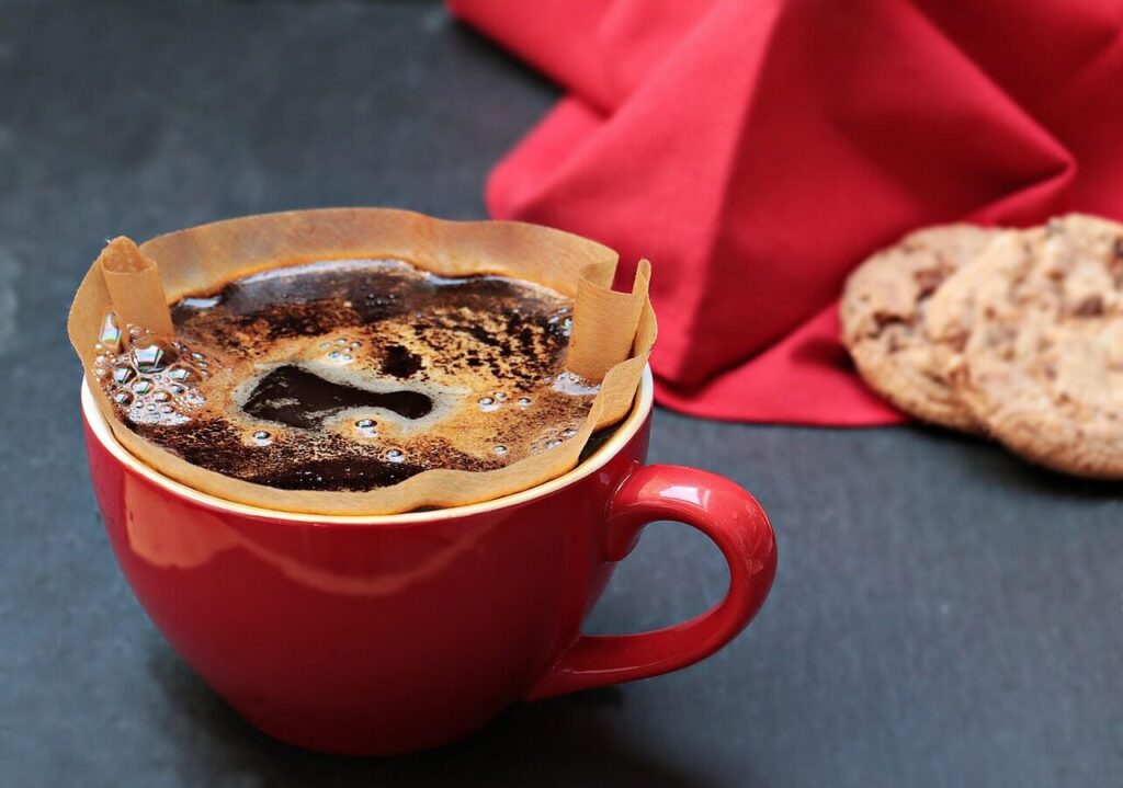 Hot coffee dripping from a pour-over dripper onto ice in a glass server