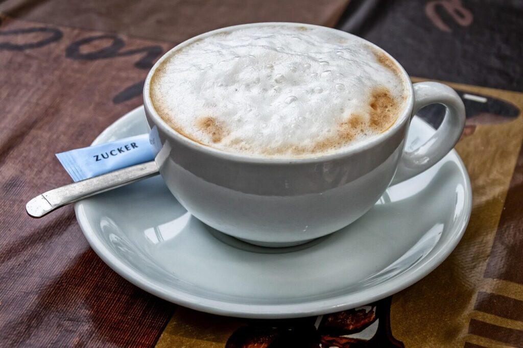 Close view of thick milk foam on top of a cappuccino in a white cup