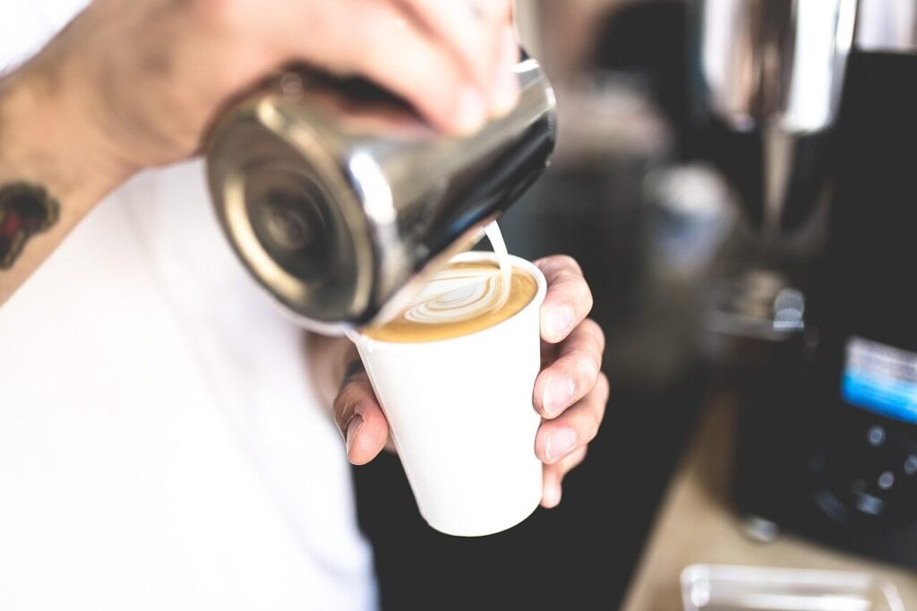 Steamed milk being poured into a cup of espresso to form a pattern